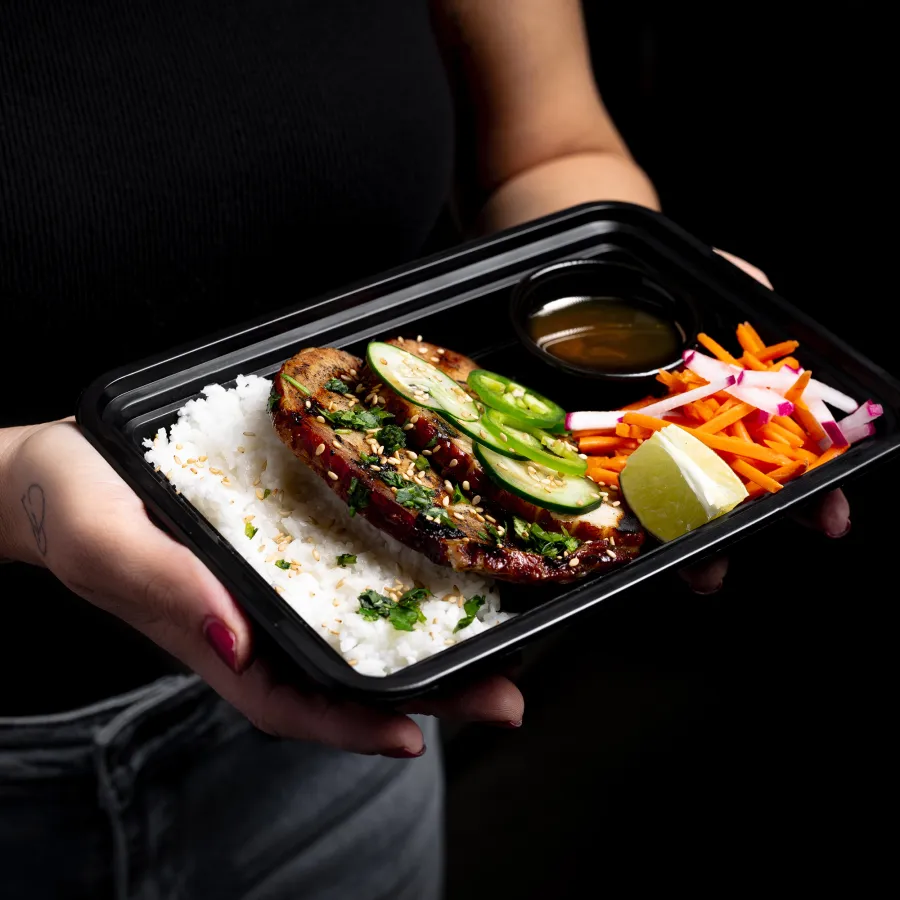 An employee holding a fresh MHP meal-prep tray